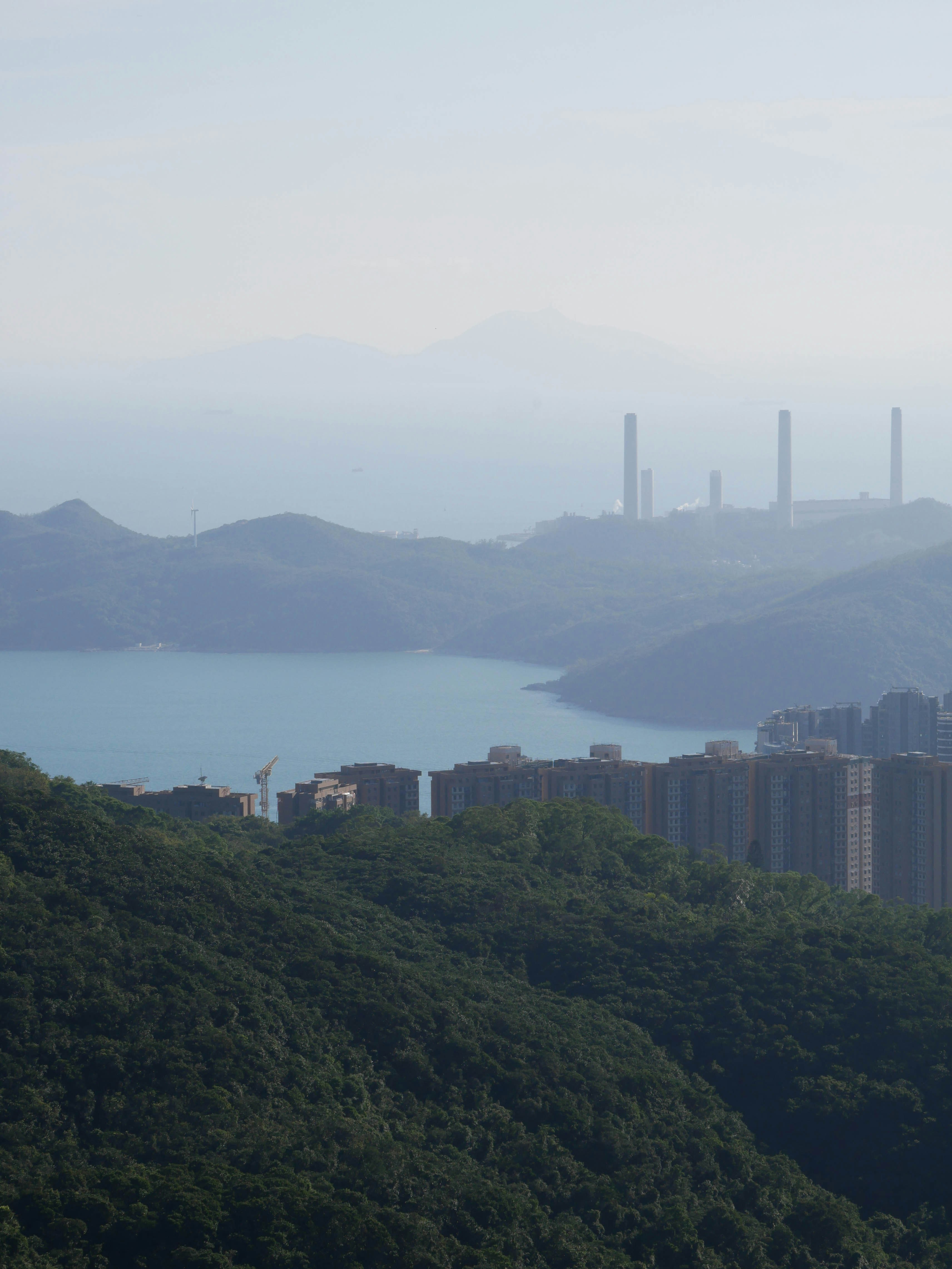 Vista nebbiosa della città costiera con ciminiere lontane.