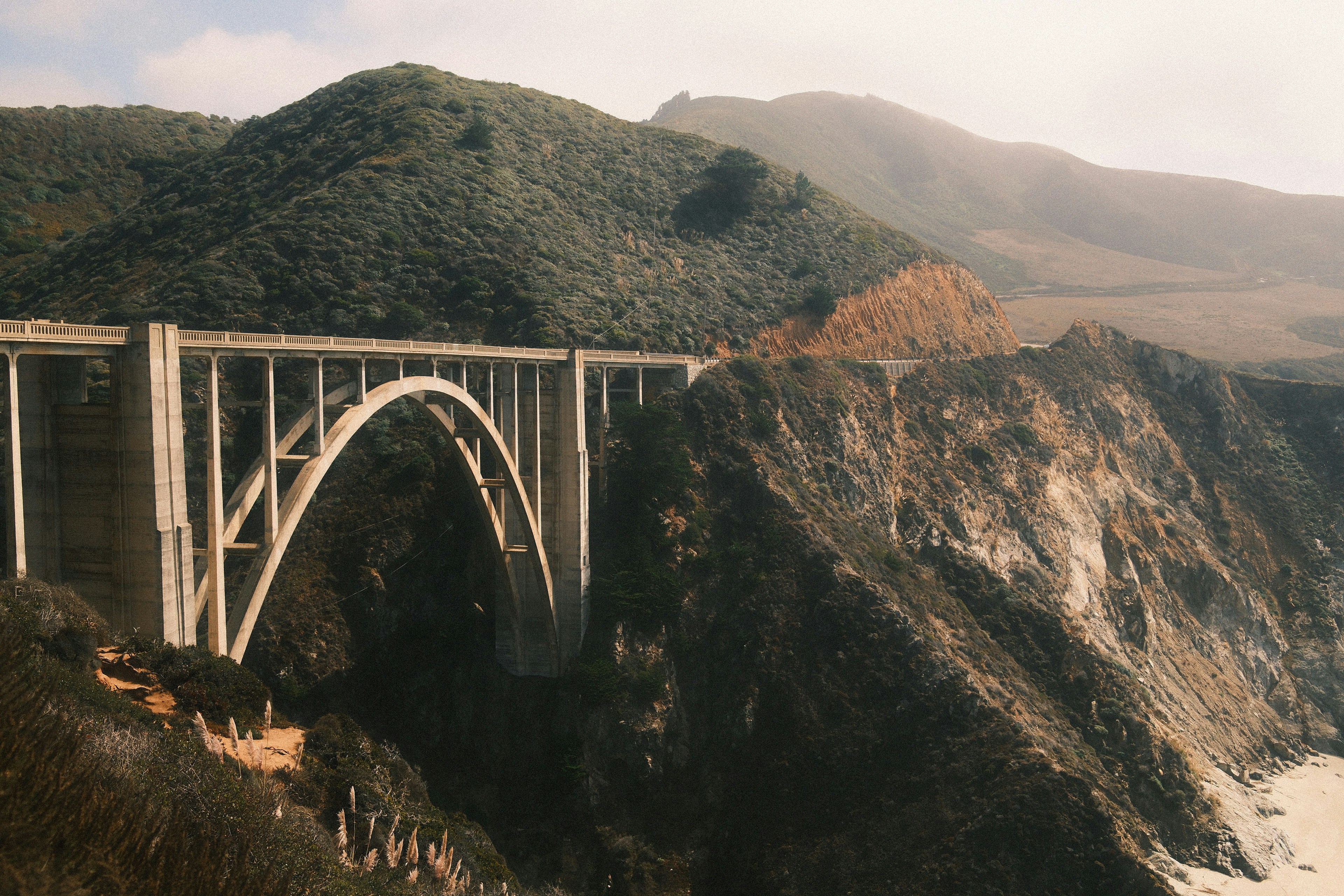 Un pont en béton enjambe une falaise rocheuse surplombant l’océan.