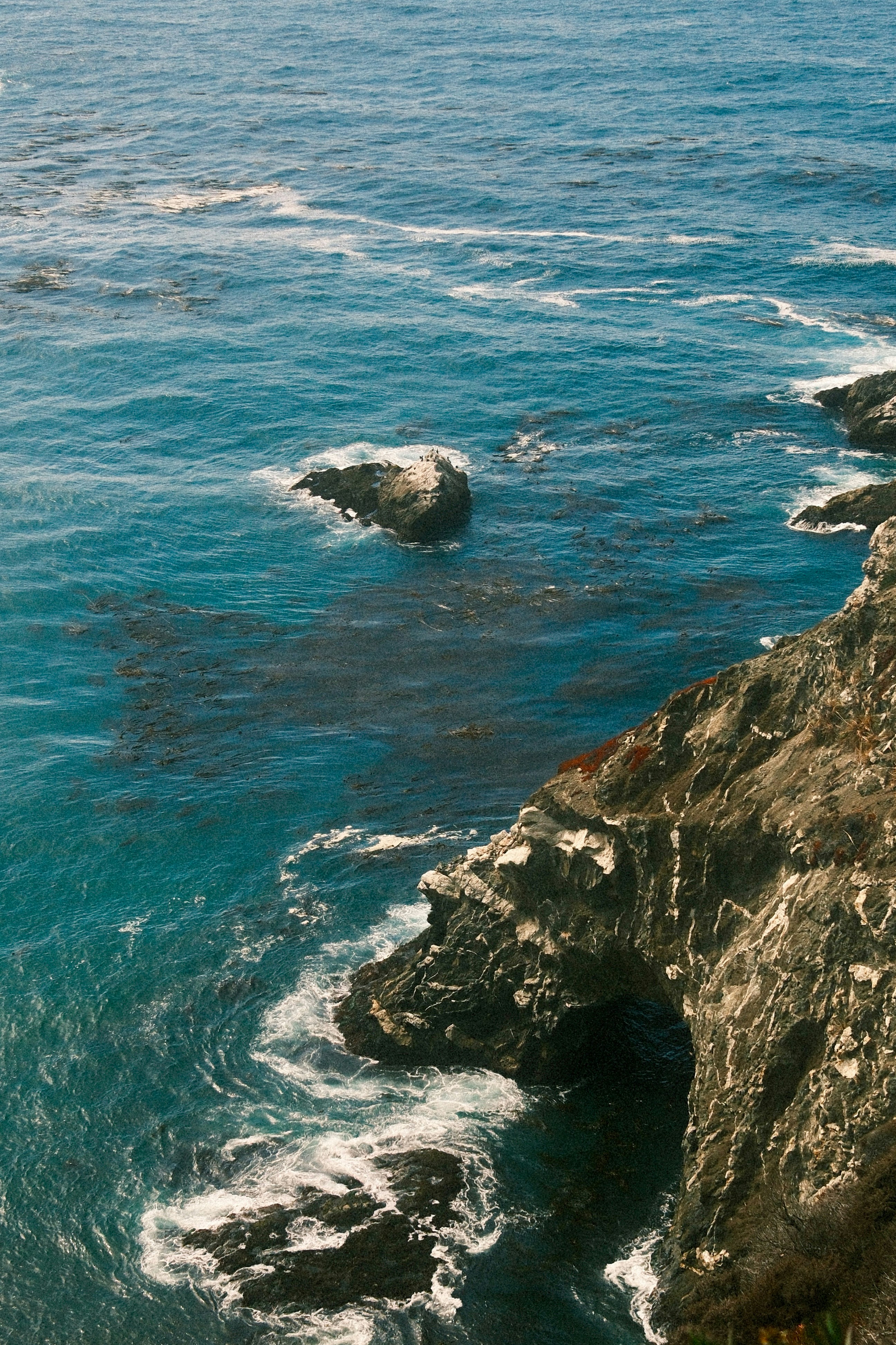 Des vagues déferlantes contre un littoral rocheux et un océan bleu.