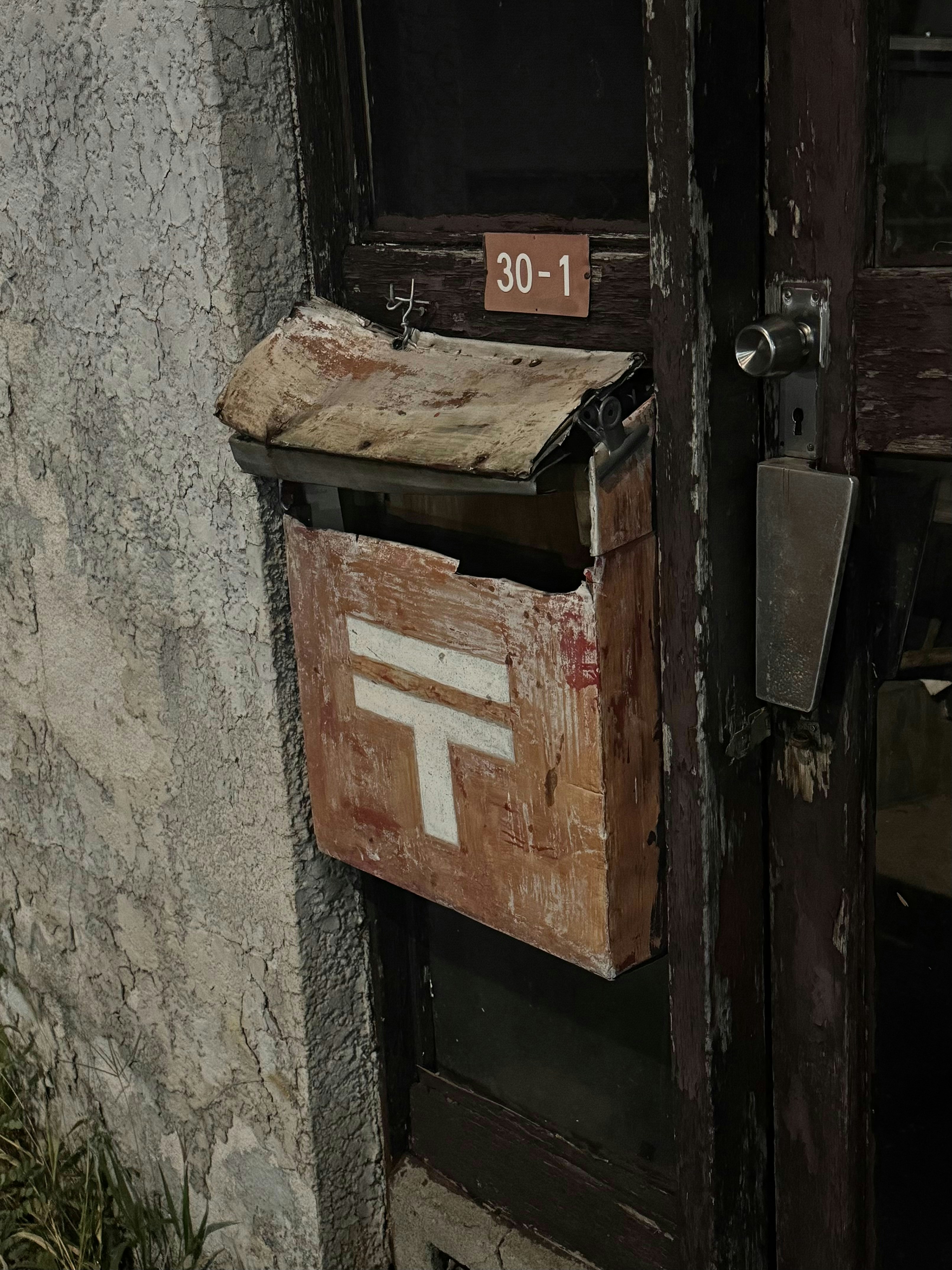 Una cassetta postale consumata dalle intemperie con un simbolo postale giapponese.