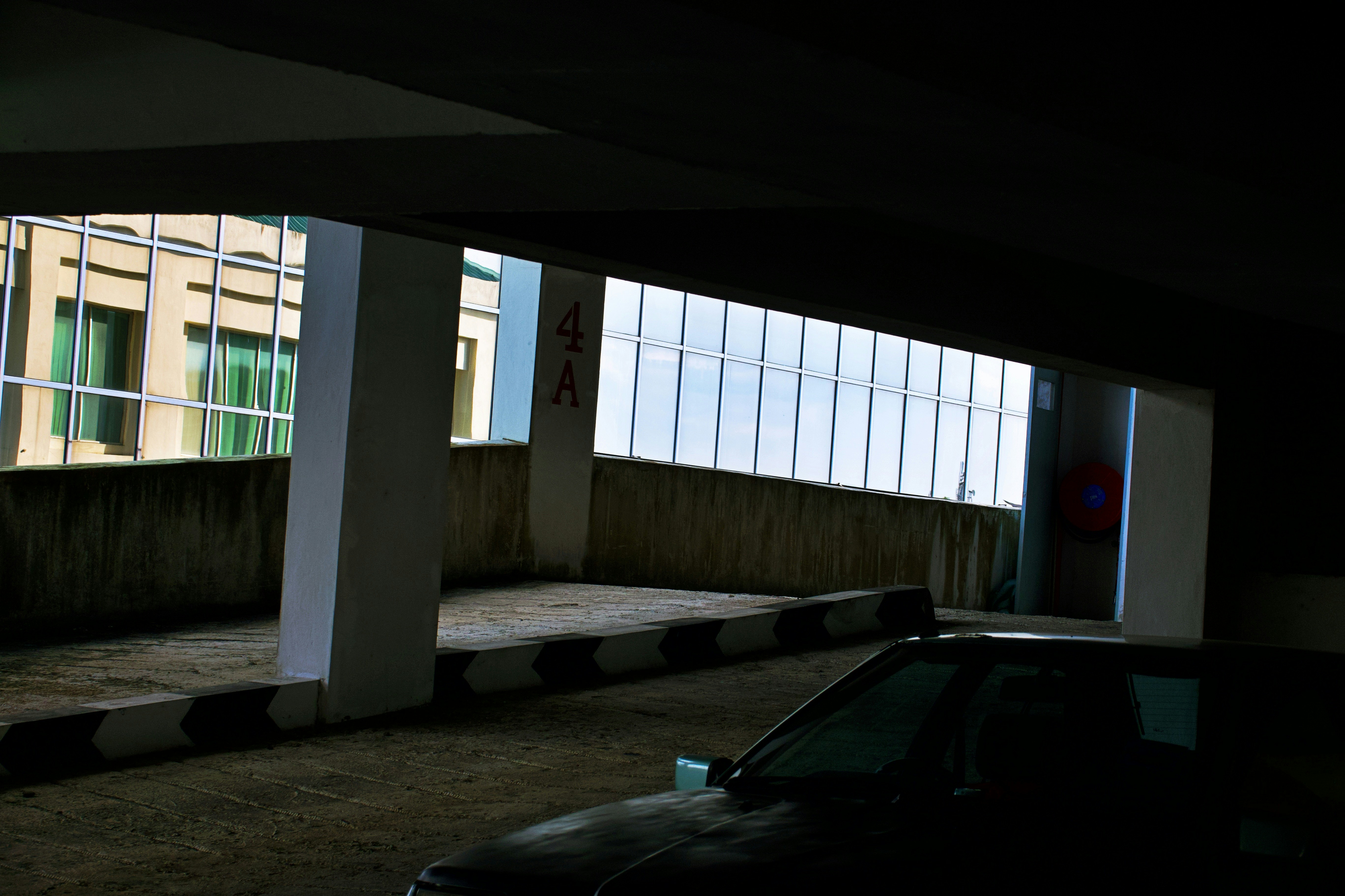Car in a dimly lit parking garage with building view.