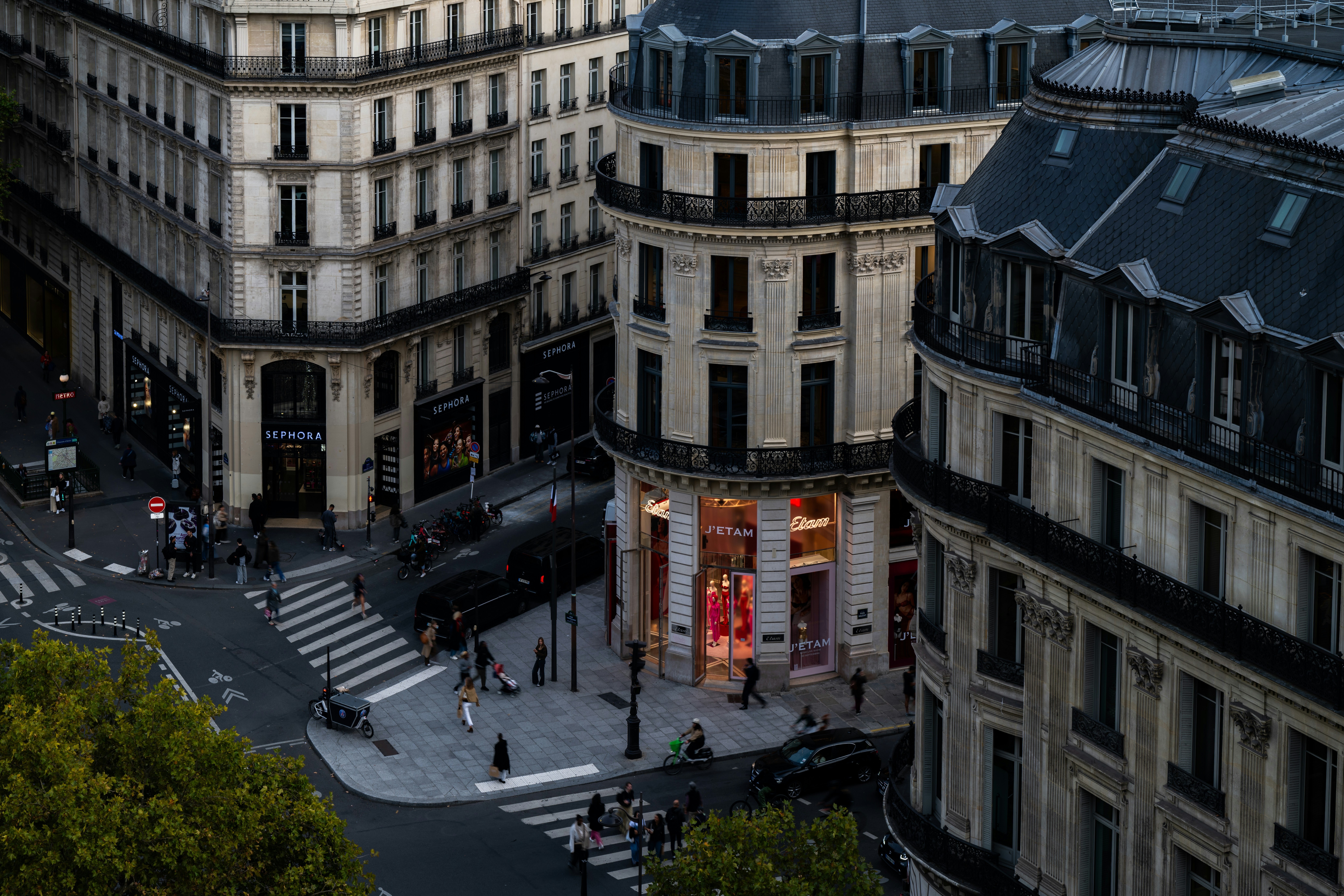 Parisian buildings and street with pedestrians crossing at dusk