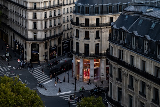Parisian buildings and street with pedestrians crossing at dusk