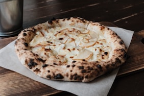 A rustic pear and cheese pizza on a wooden board.