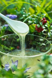 Honey dripping from spoon into a glass bowl