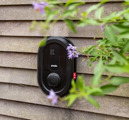 Black electric car charger mounted on wooden wall