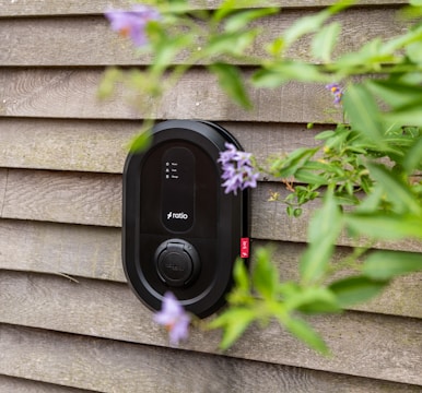 Black electric car charger mounted on wooden wall