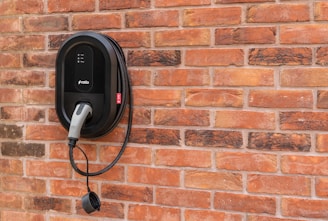 Black electric car charger mounted on brick wall