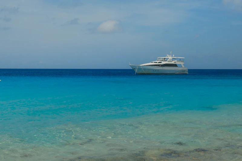 A white superyacht at anchor in clear turquoise Caribbean water