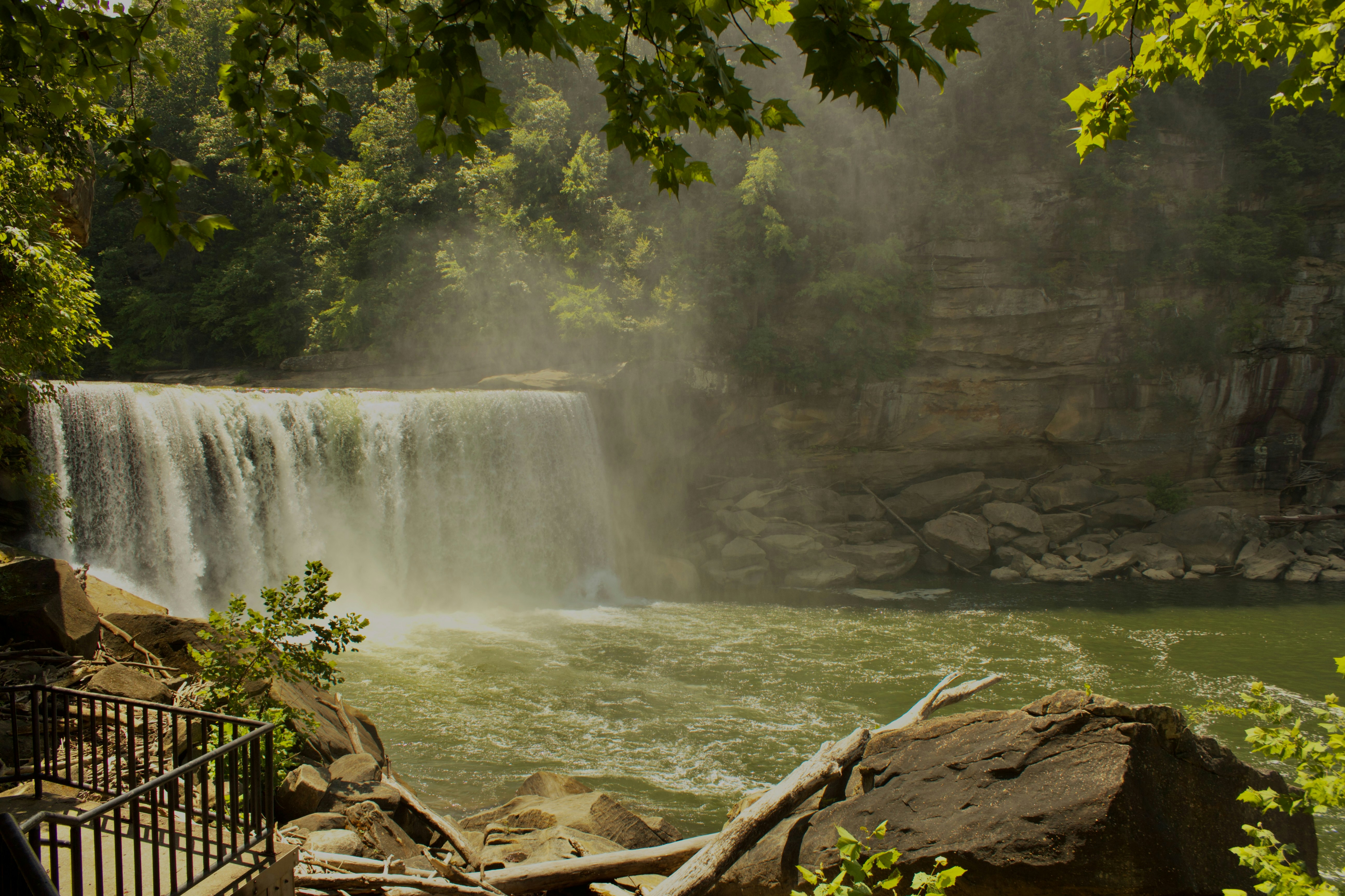 広い滝が緑豊かな川に流れ落ちます。
