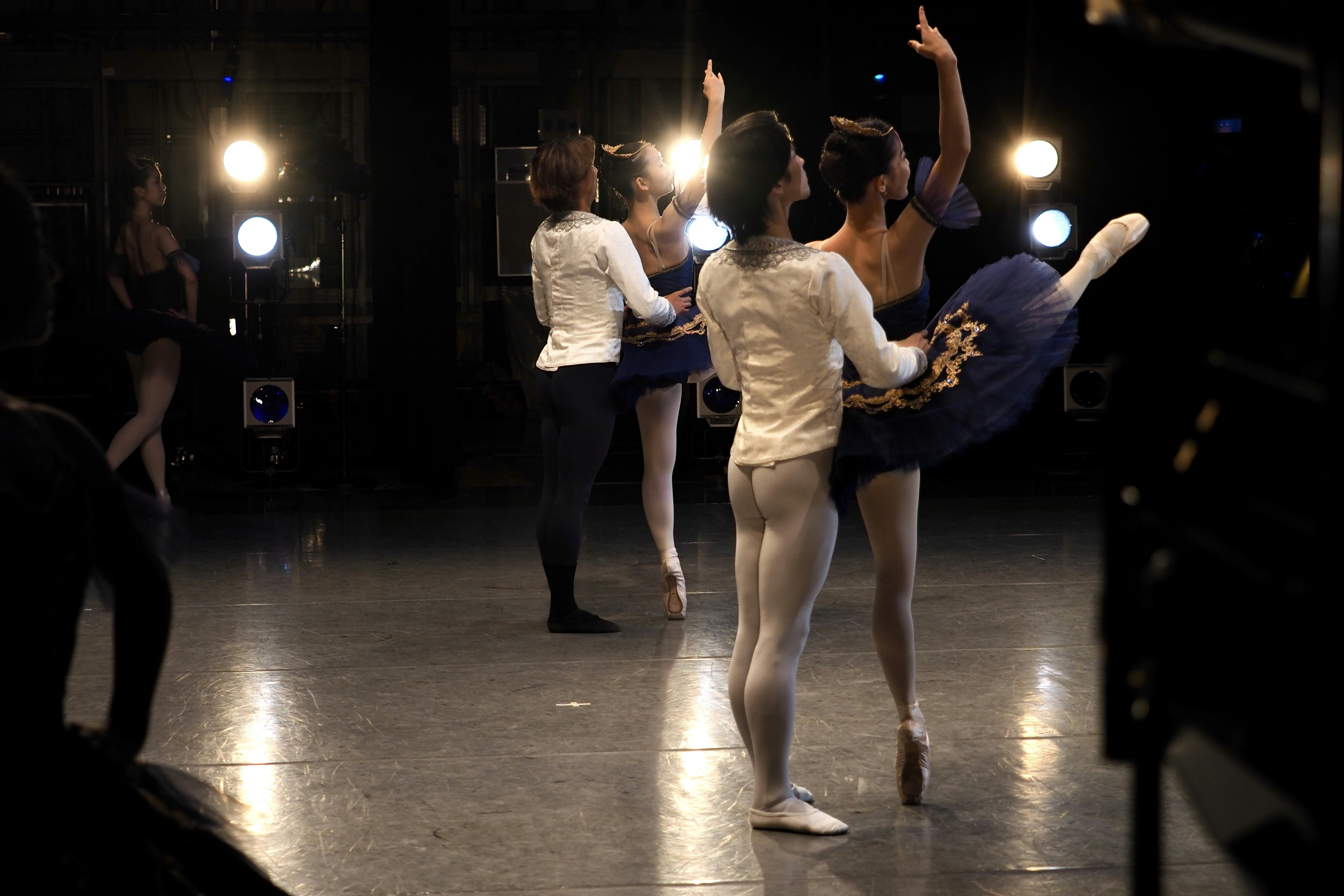 Ballet dancers practicing on a stage with spotlights.