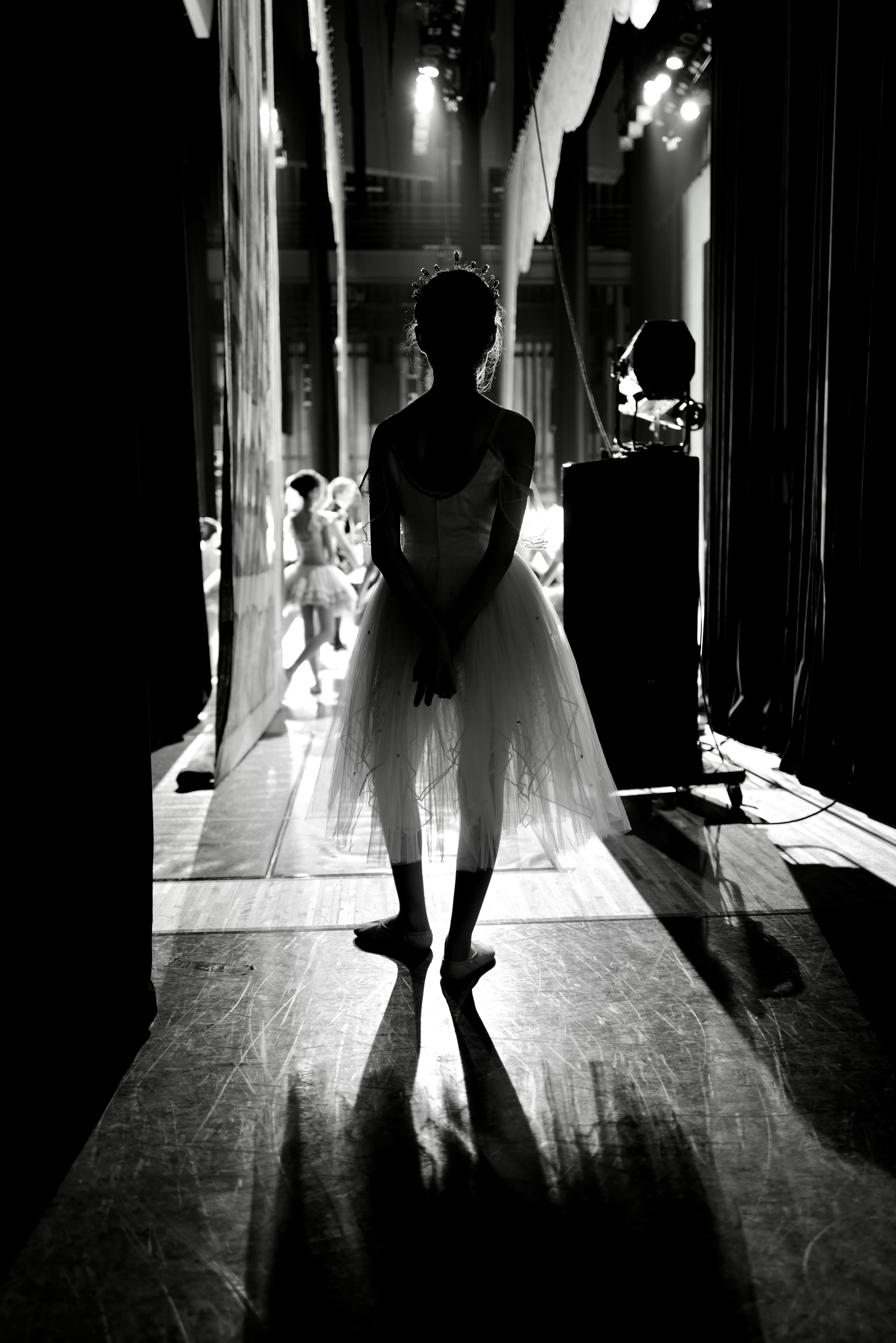 Ballerina in tutu backstage with dramatic lighting.