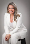 A professional woman in a white suit smiles.