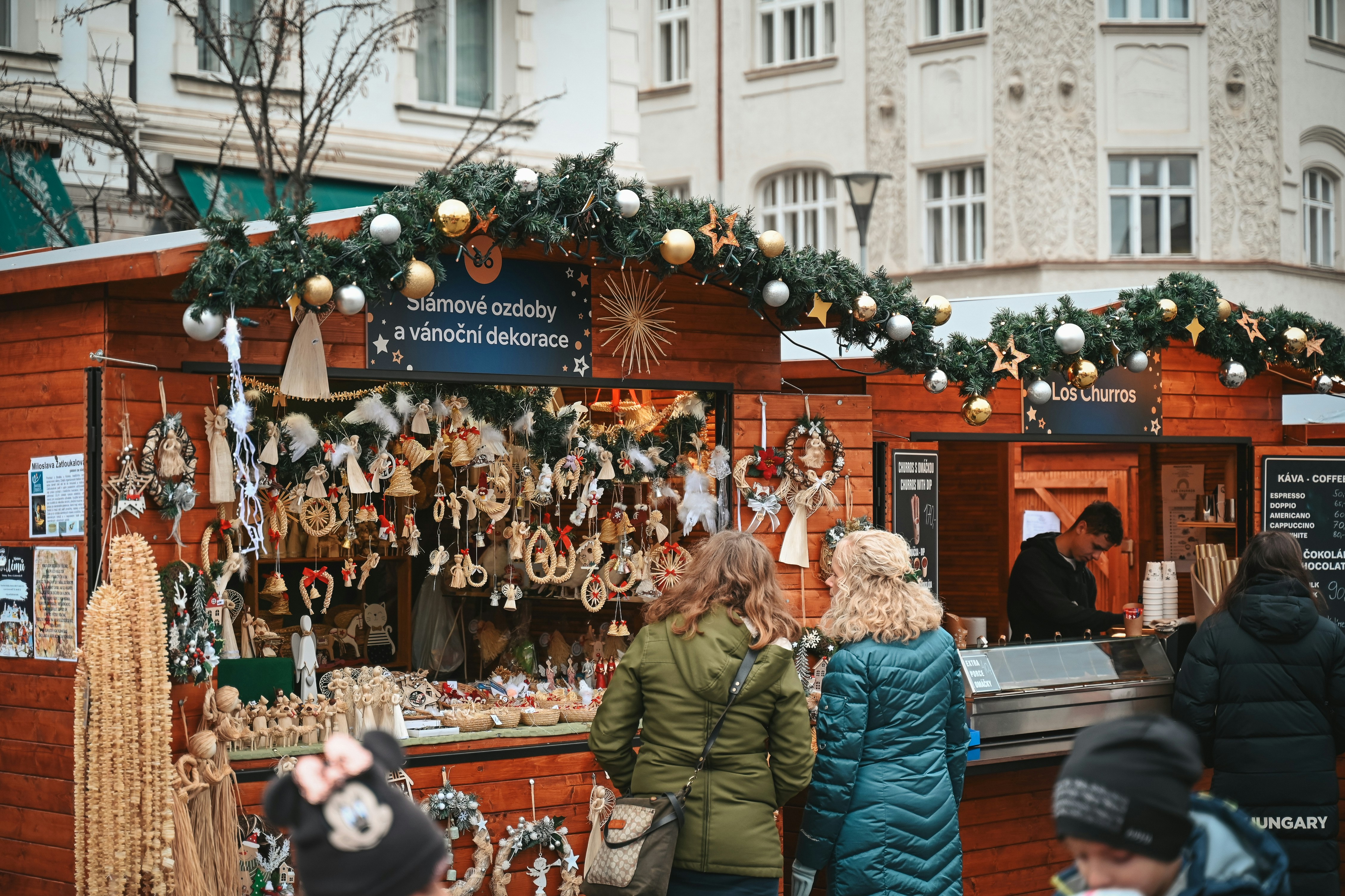 People browse christmas market stalls with decorations.