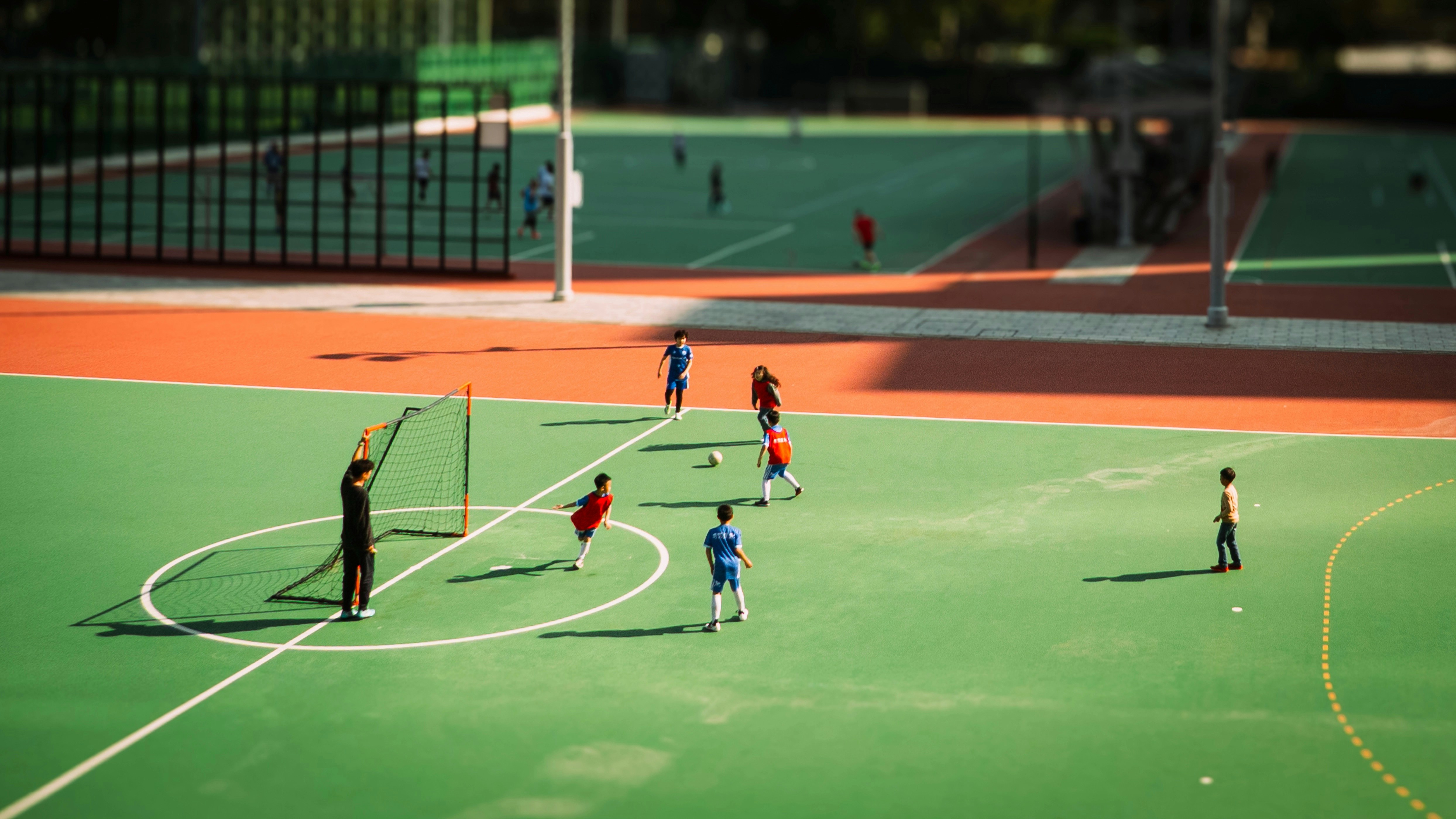 People playing soccer on a green outdoor court.