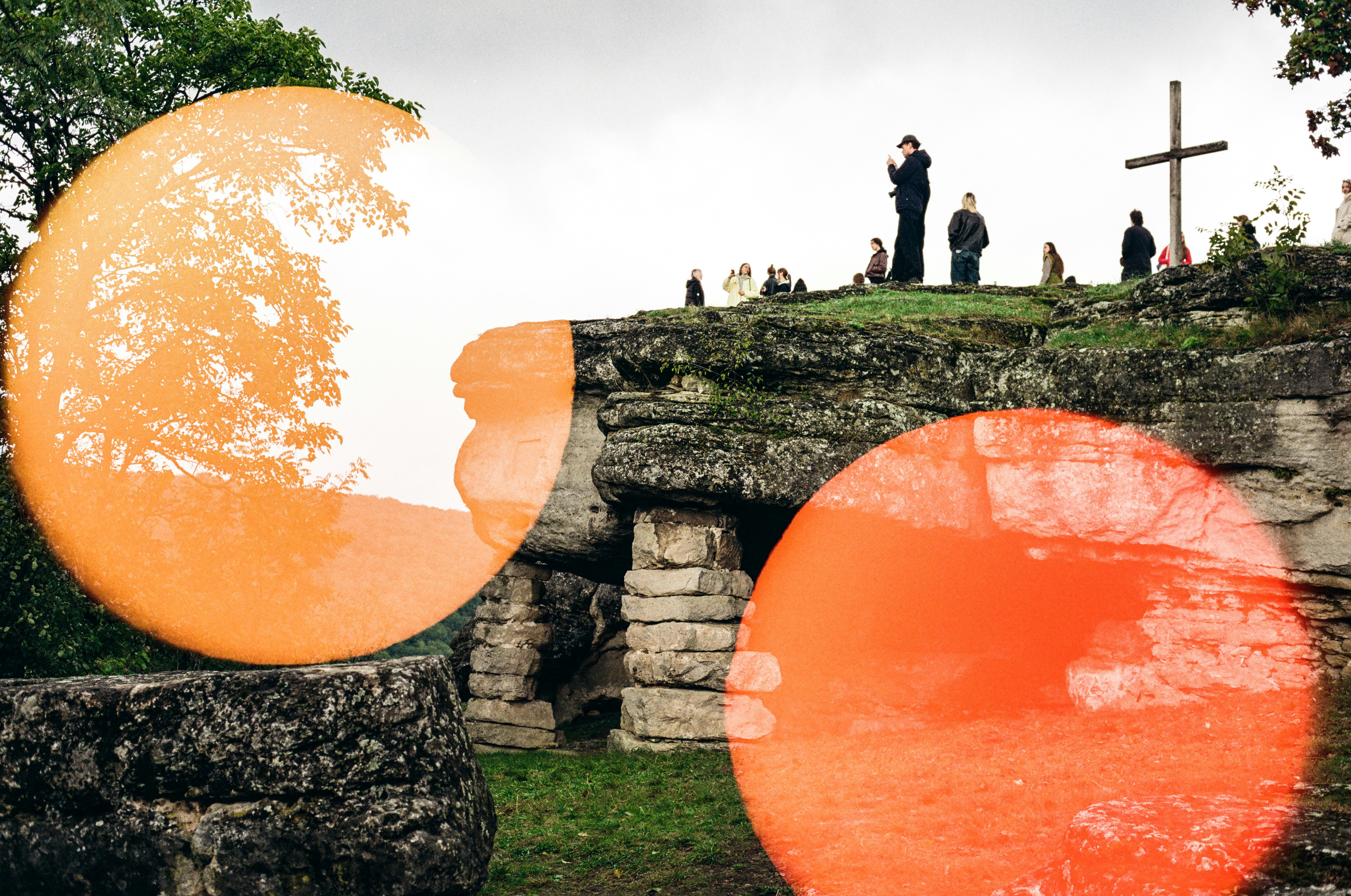 Dos círculos naranjas oscurecen antiguas ruinas de piedra y personas.