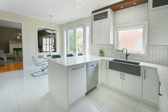 Modern white kitchen with island and dining area.