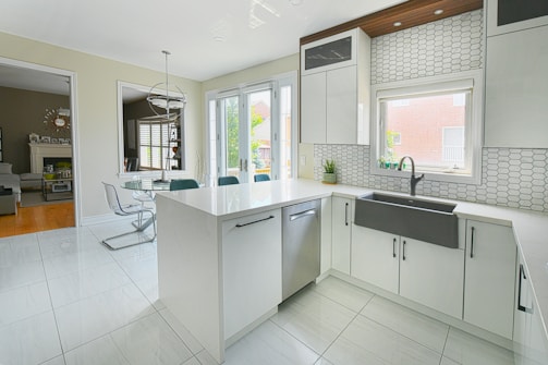 Modern white kitchen with island and dining area.
