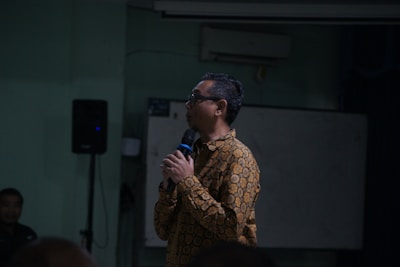 Man in patterned shirt speaks into microphone