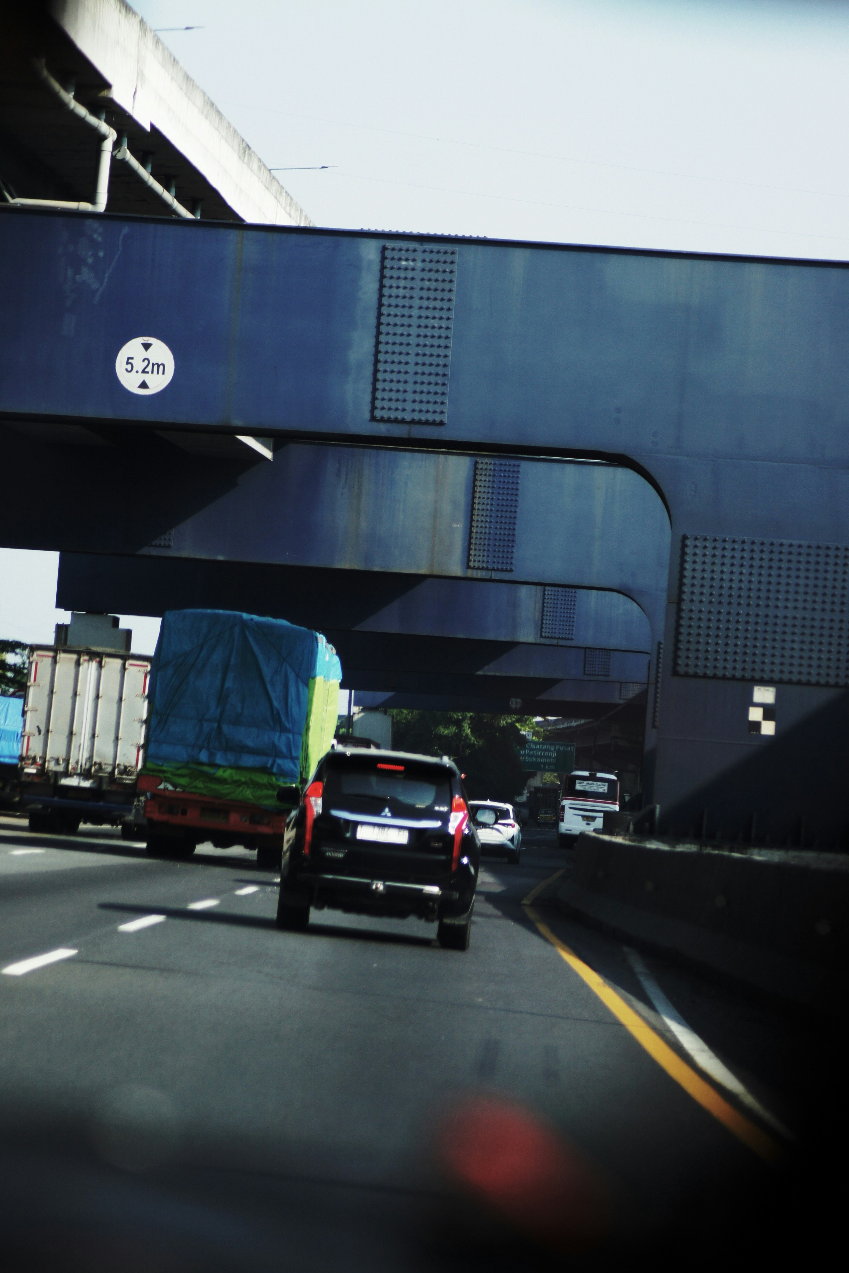 Cars driving on a highway under an overpass.