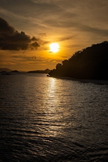 Golden sun setting over a calm ocean and island.