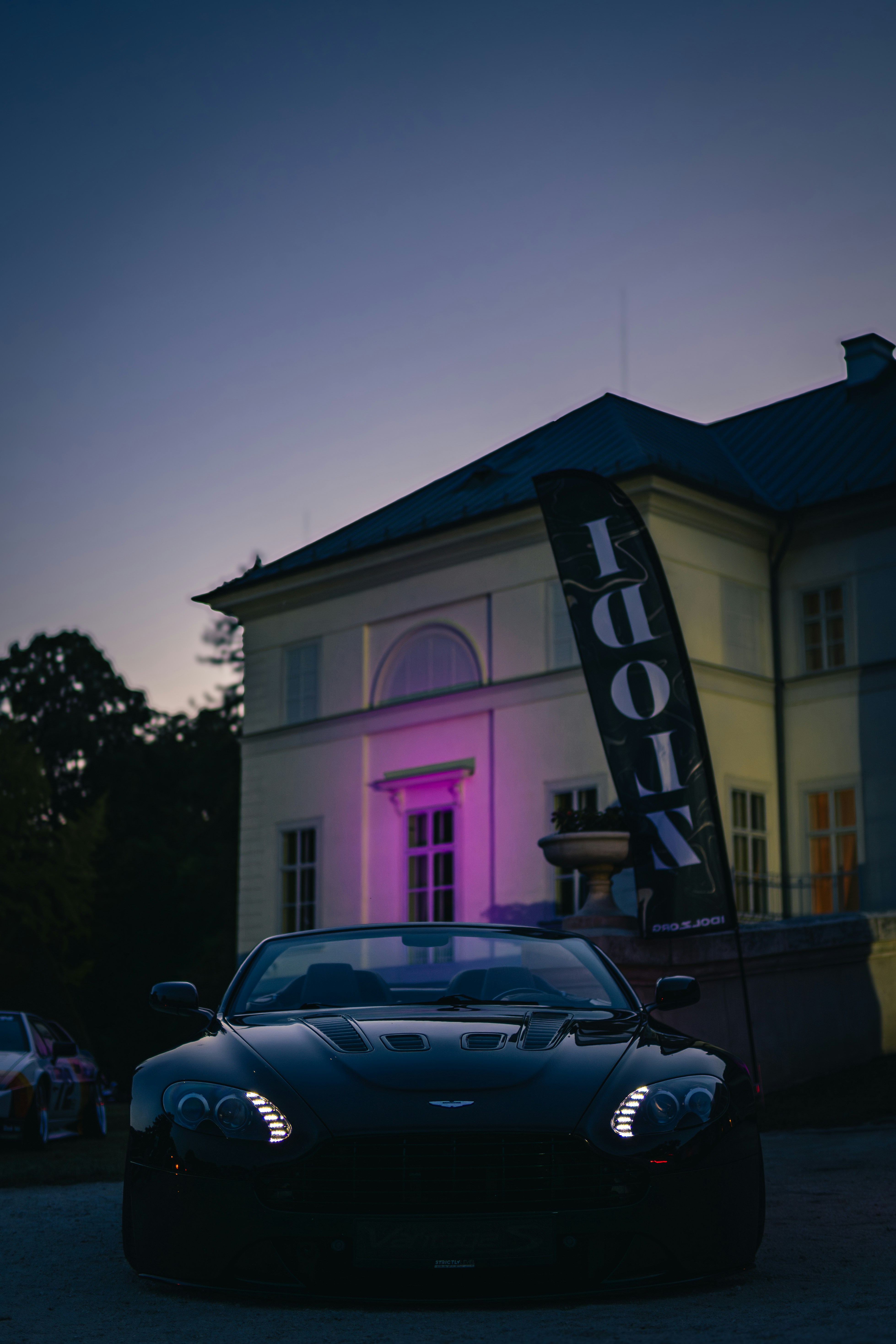 Black convertible car parked near a building at dusk.