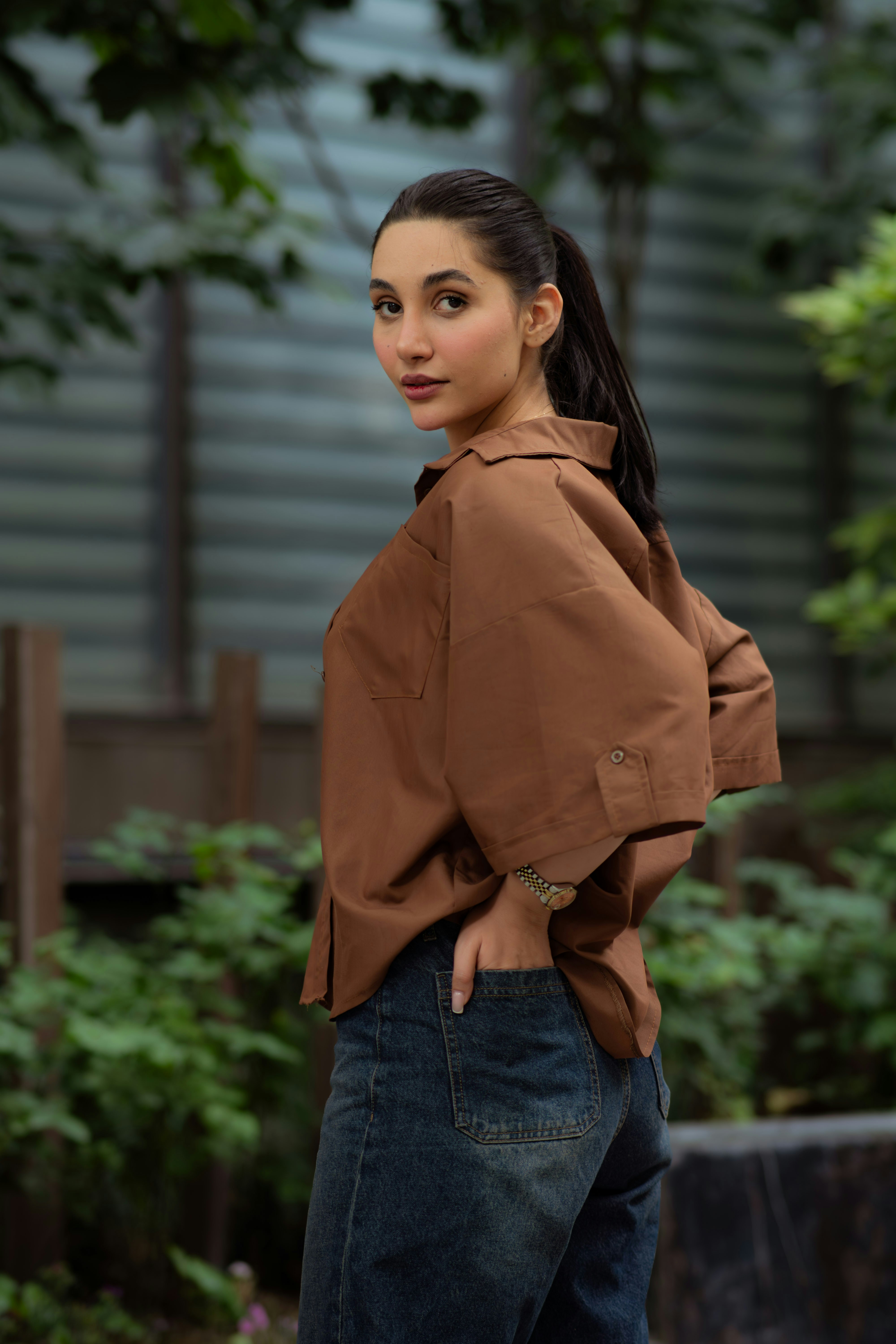 Young woman in brown shirt and jeans outdoors