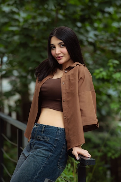 A young woman in a brown shirt and jeans outdoors
