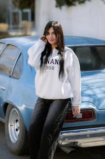 Young woman leaning against a vintage blue car