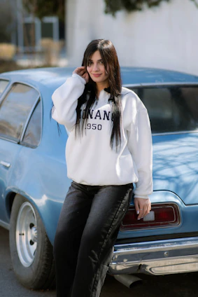 Young woman leaning against a vintage blue car