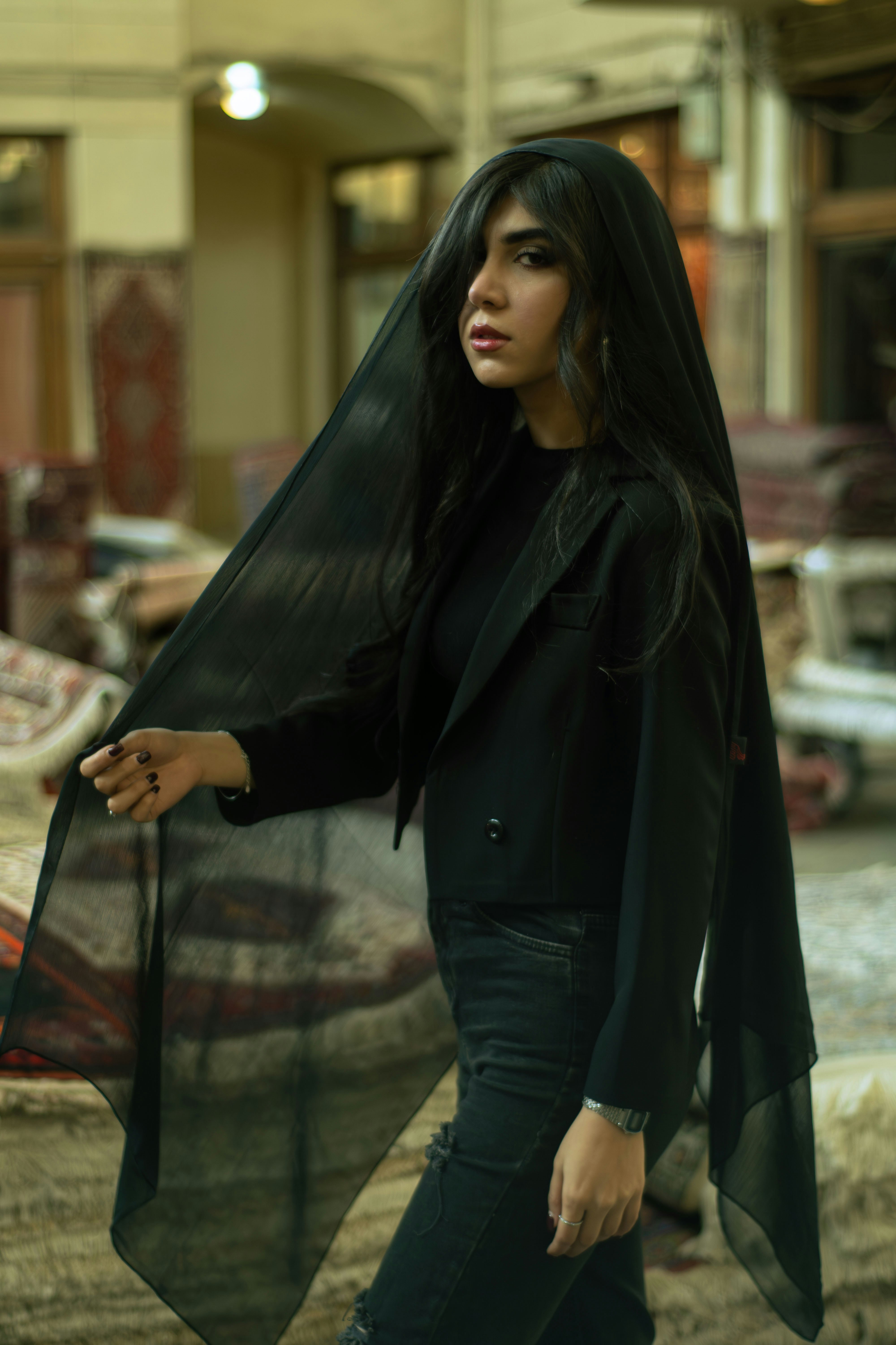 A woman in a black veil and jacket indoors