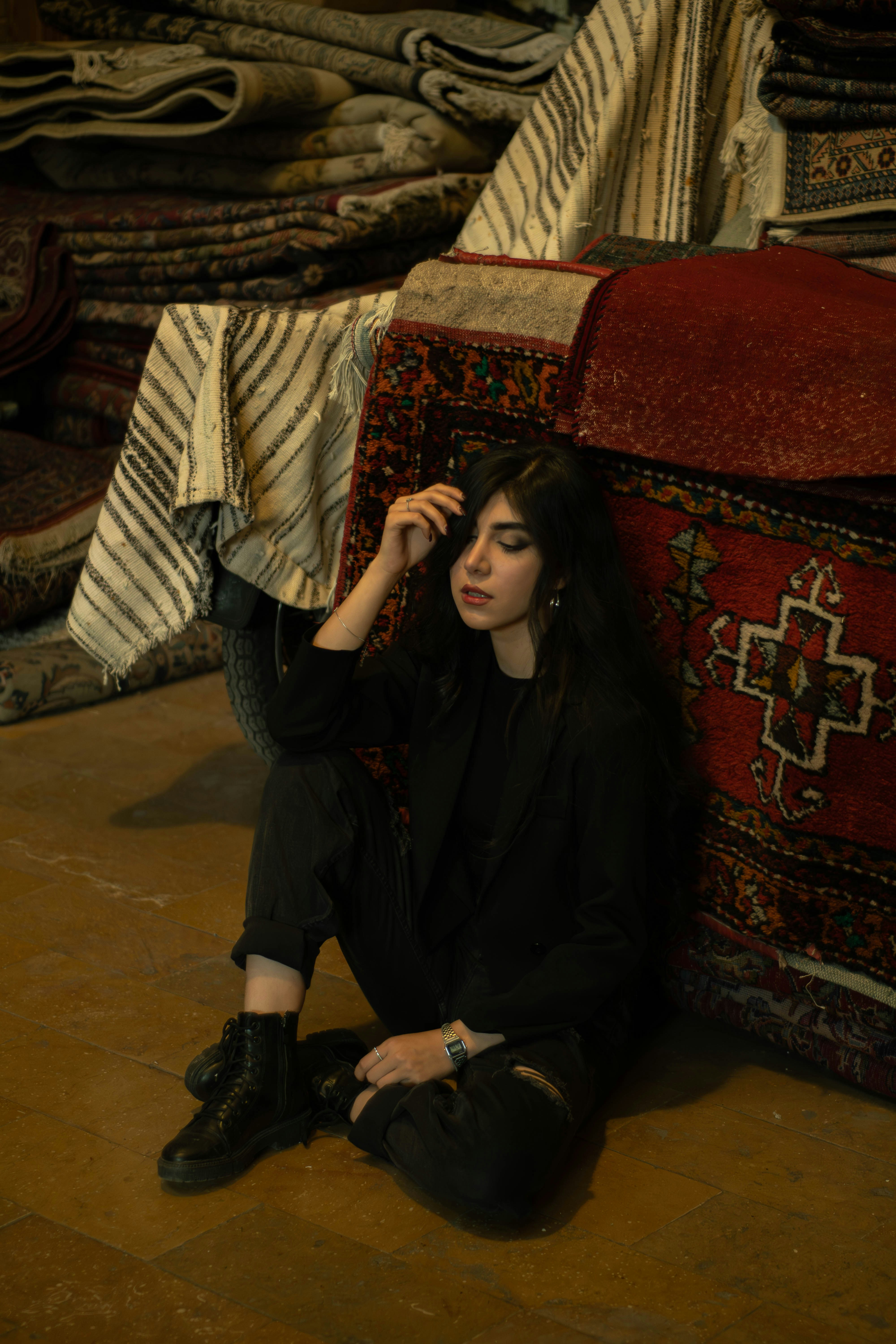 Woman sitting among stacked carpets