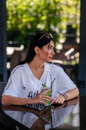 Woman holding a refreshing drink at an outdoor cafe.
