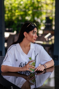 Woman holding a refreshing drink at an outdoor cafe.