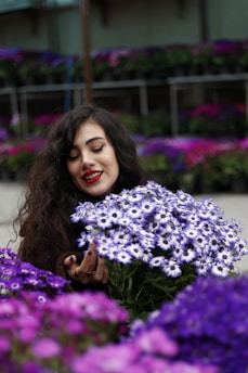 Woman holding a bouquet of purple and white flowers.