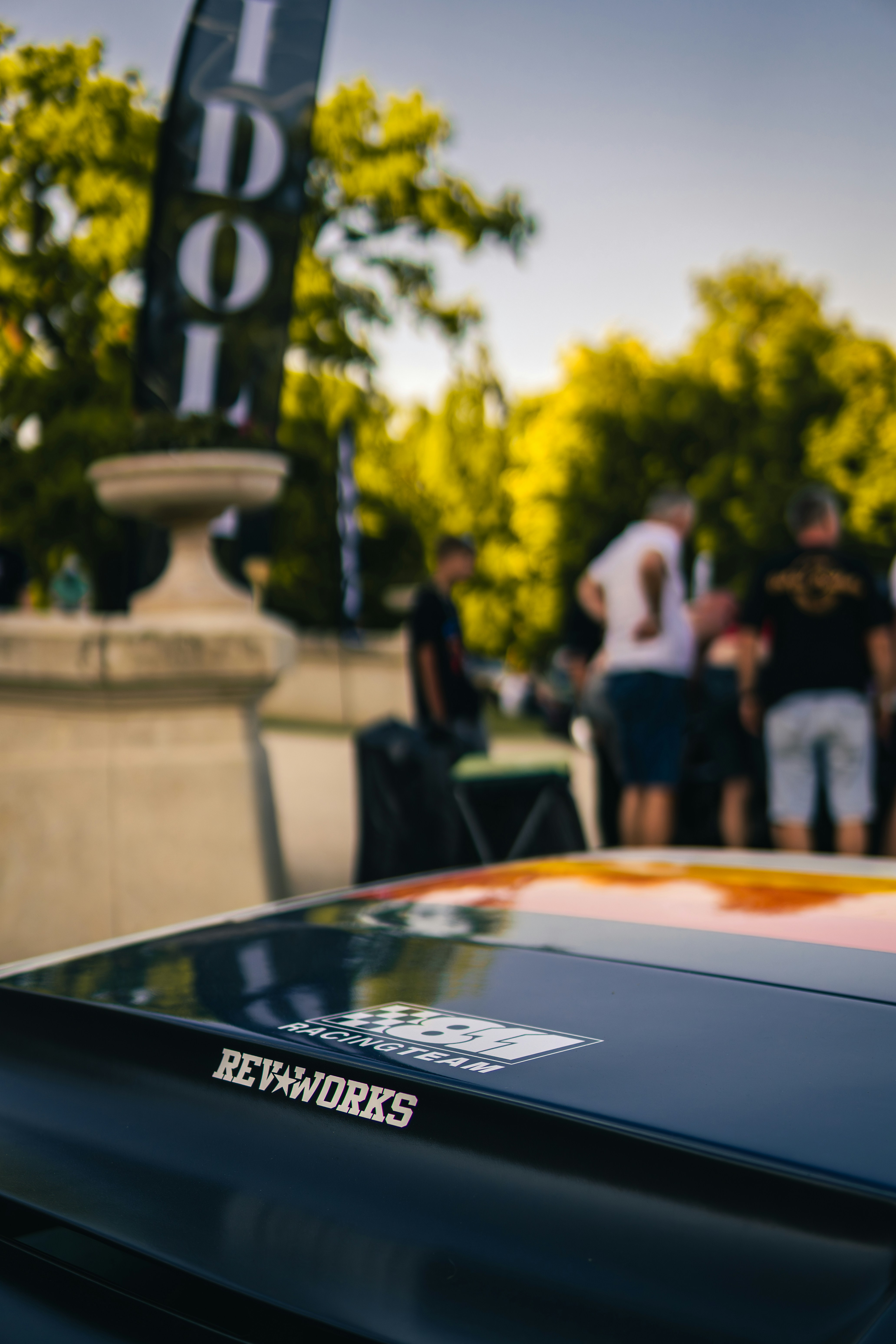 Car hood with stickers and people in background