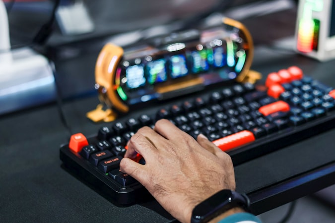 Person's hand typing on a gaming keyboard with colorful lighting