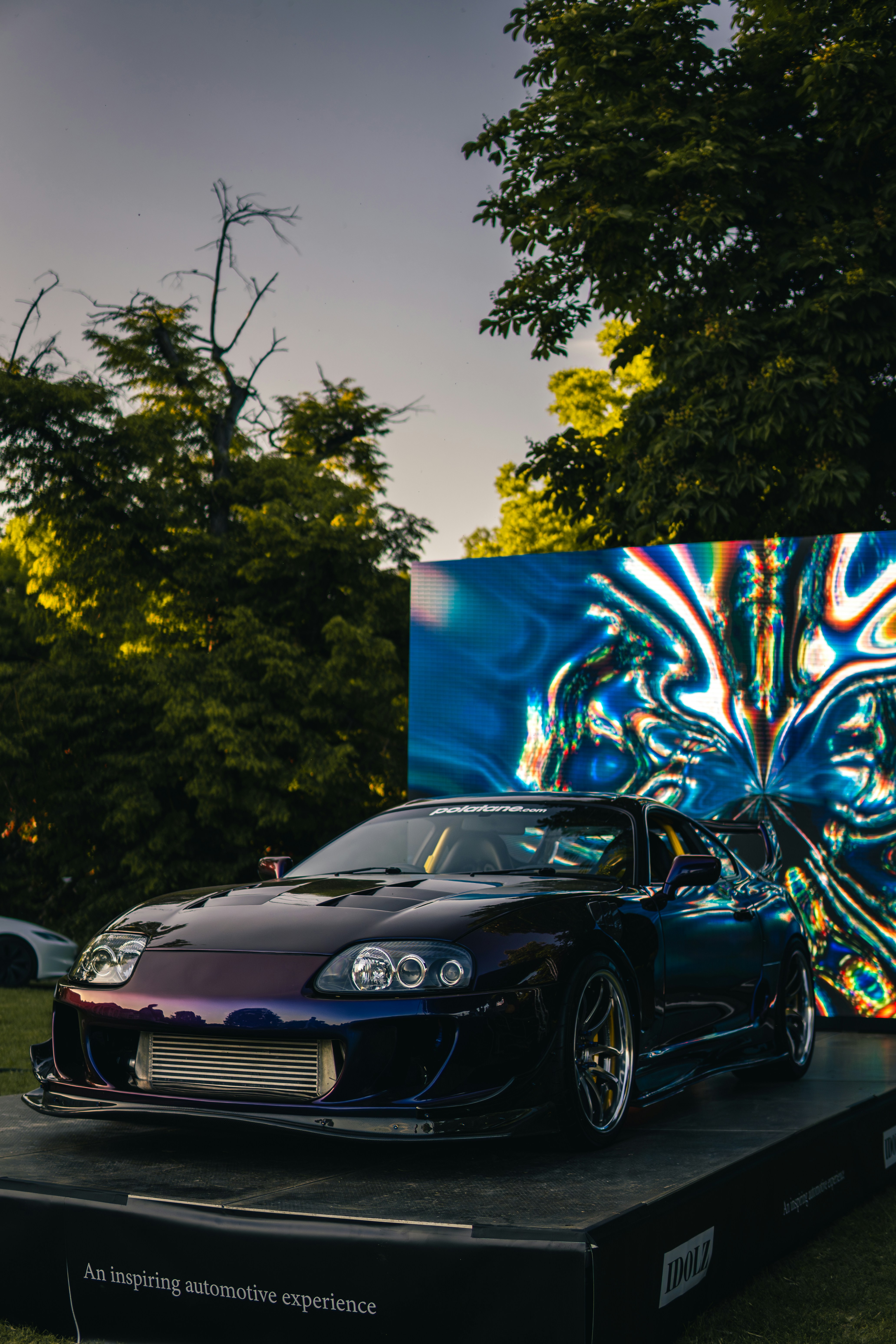 カラフルなディスプレイで屋外に駐車された紫色のスポーツカー。