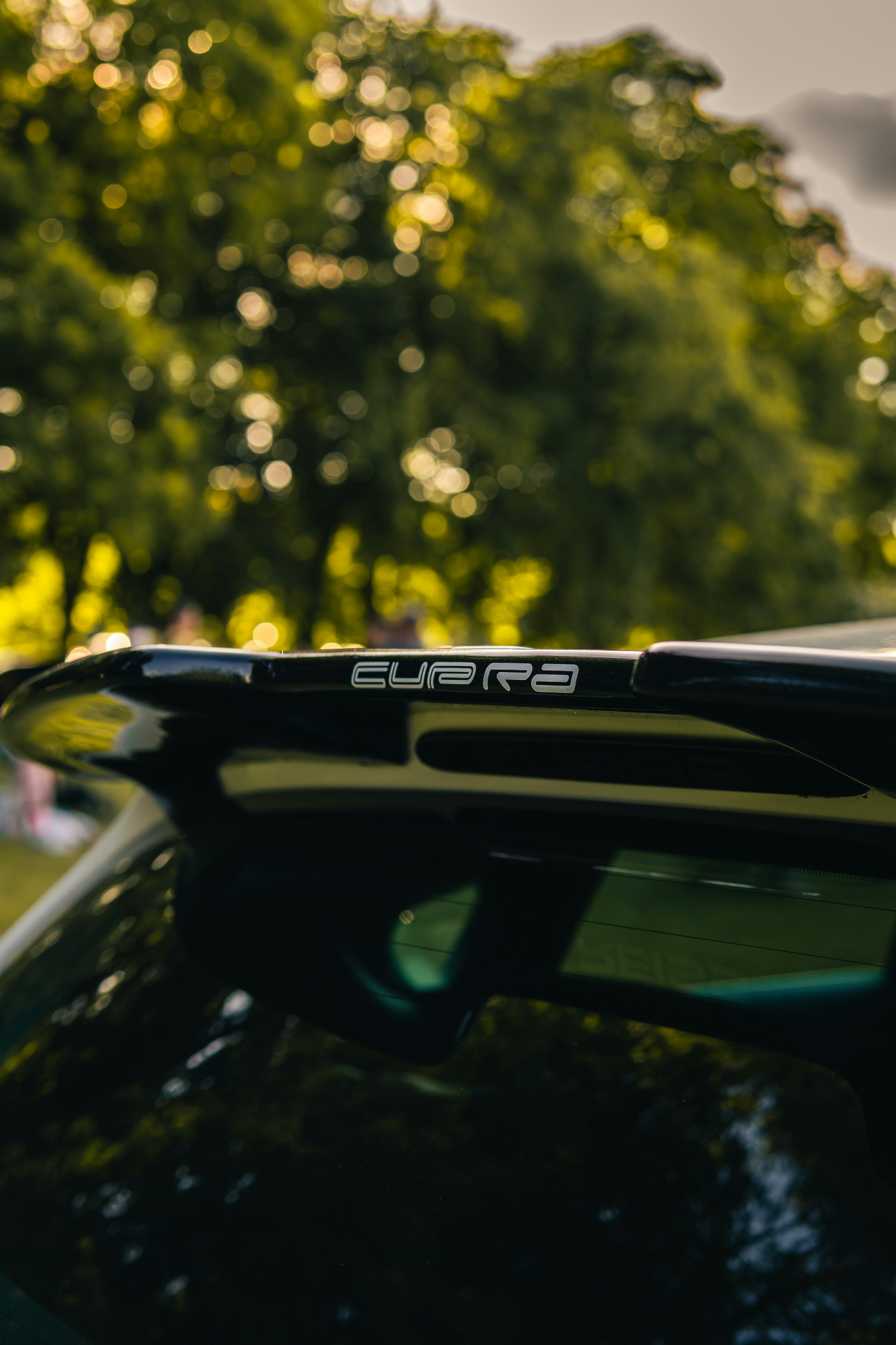 キュプラのロゴが入った黒い車のスポイラーのクローズアップ。