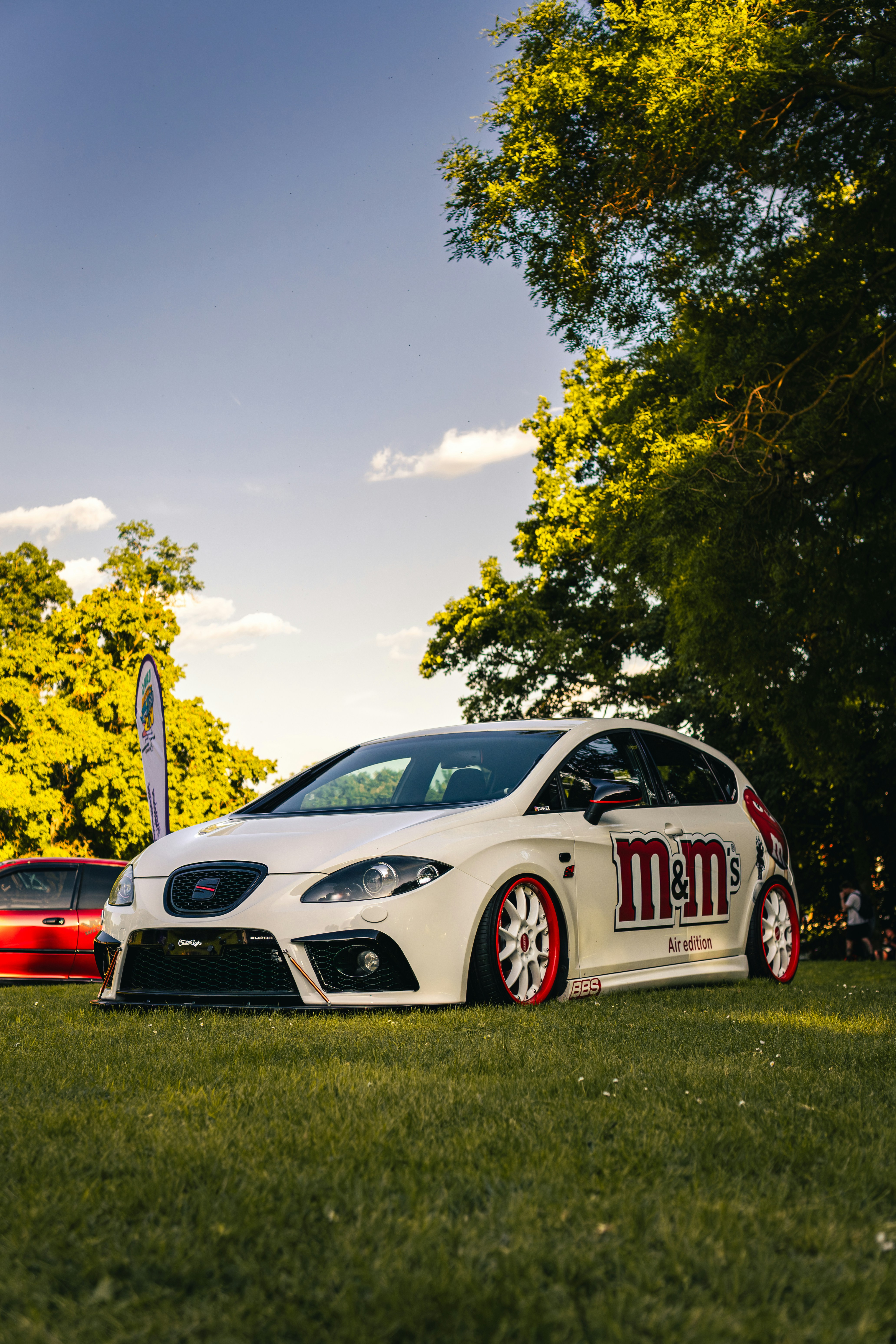芝生に赤いアクセントが効いた白い改造車。