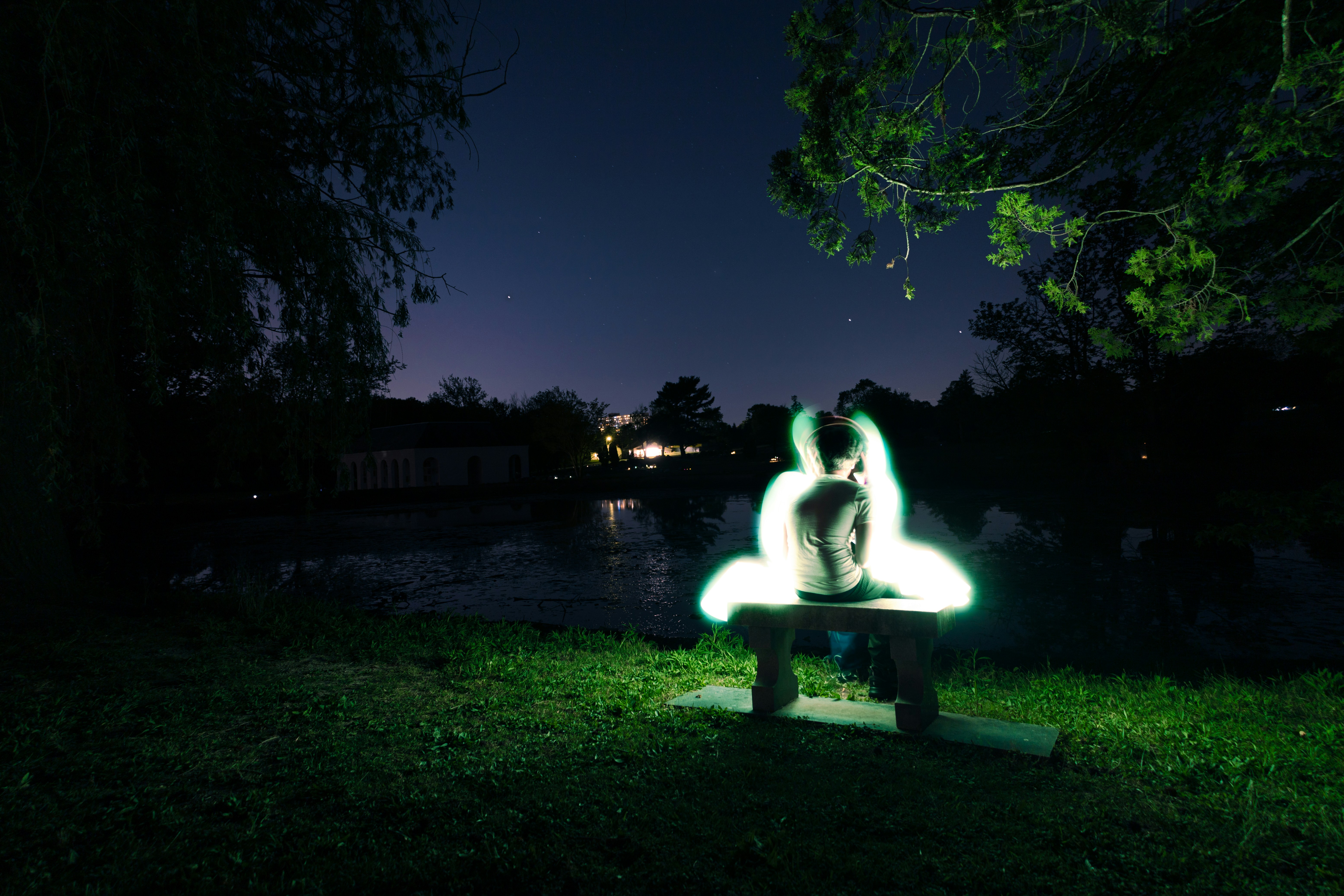 Person illuminated by light painting on bench at night