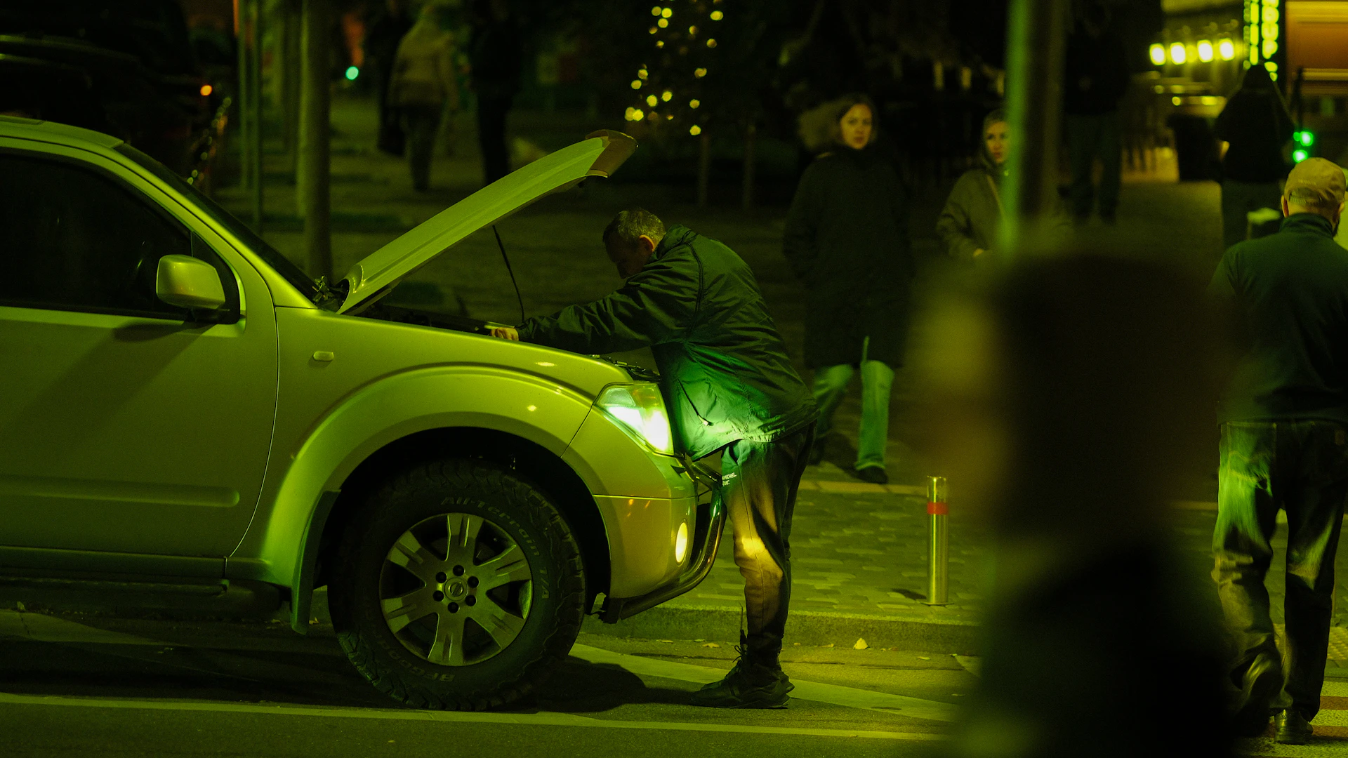 Man looking at car engine at night