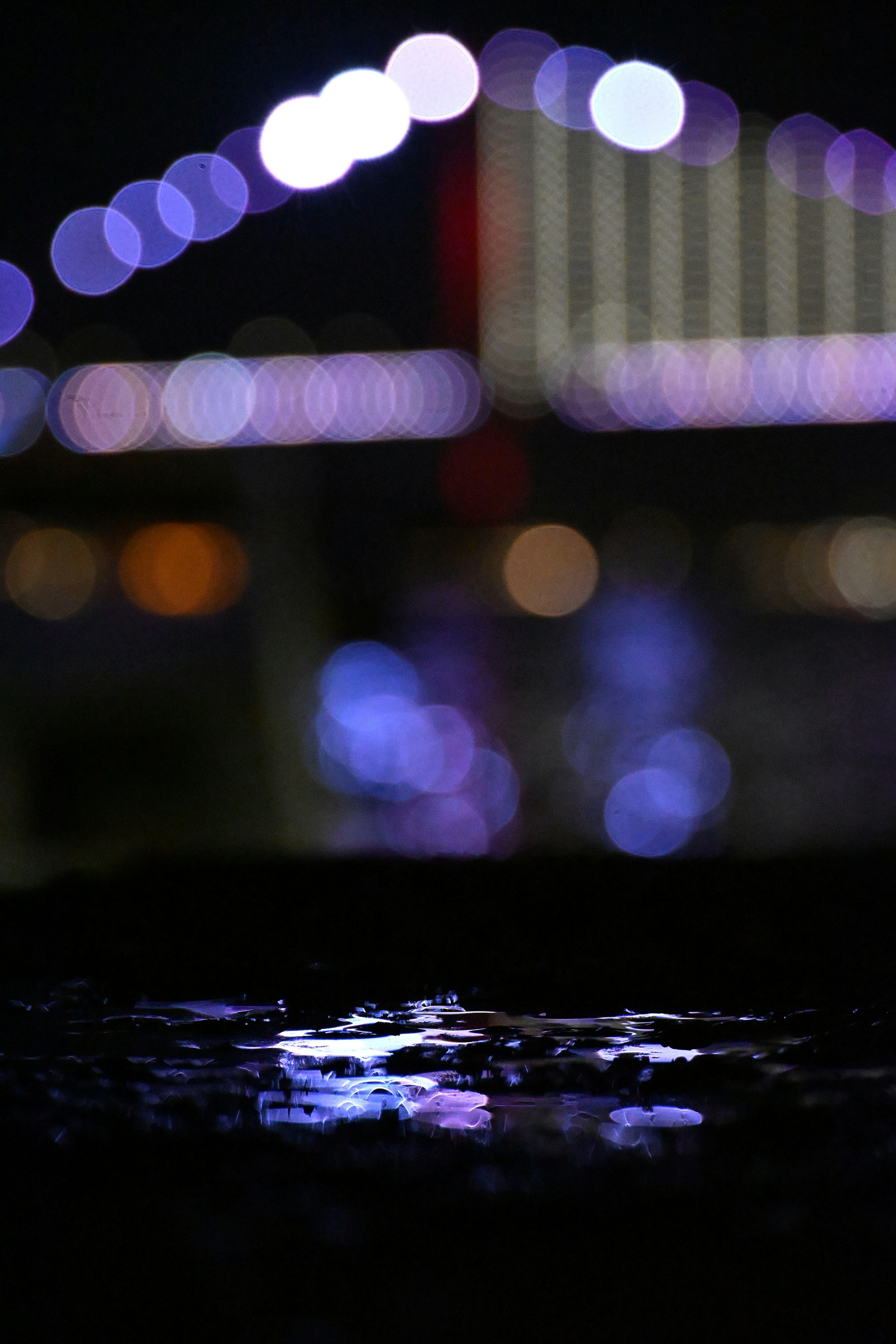 Blurred city lights reflect on wet ground at night