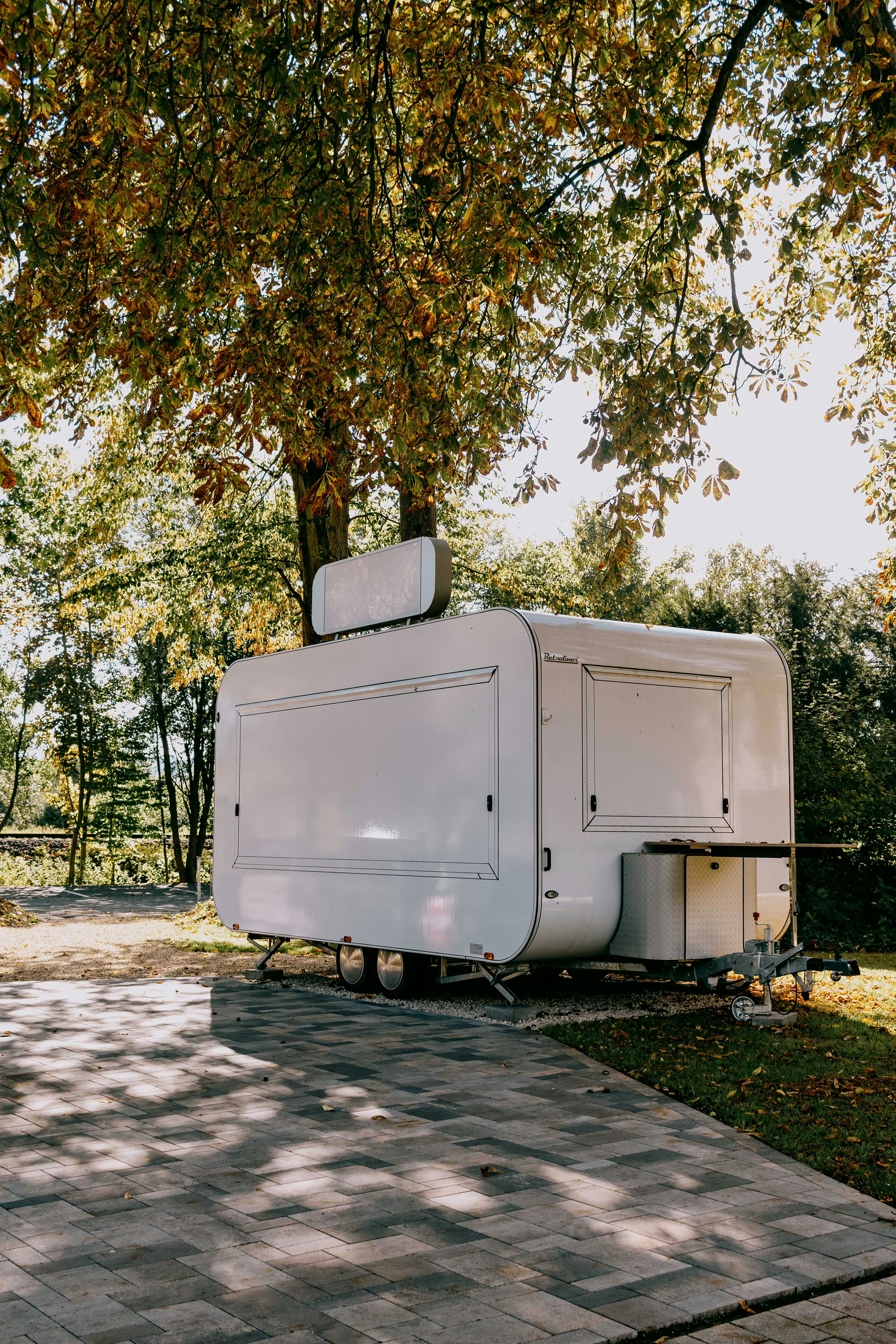 White food trailer parked under autumn trees