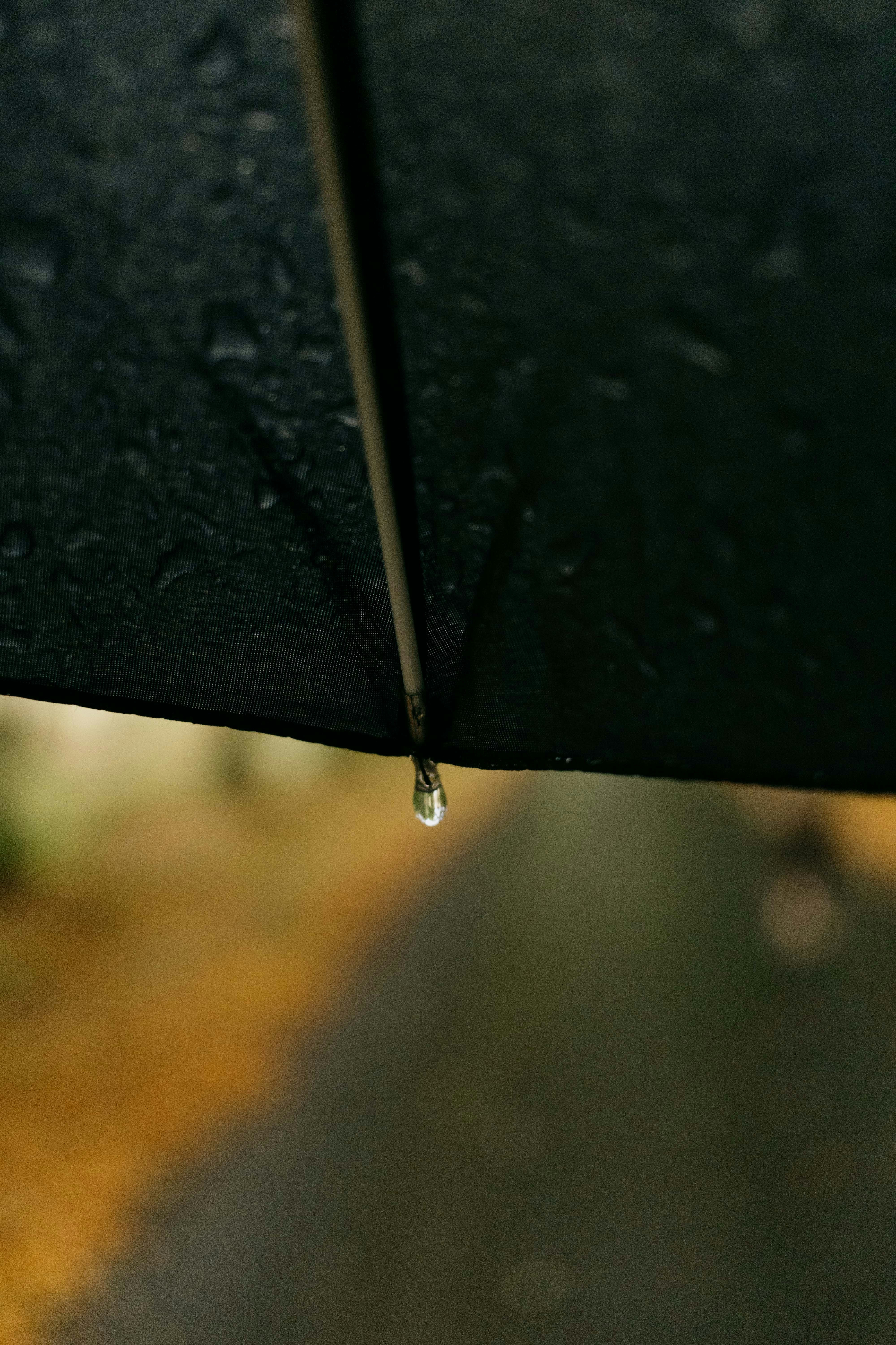 A single raindrop falls from an umbrella.