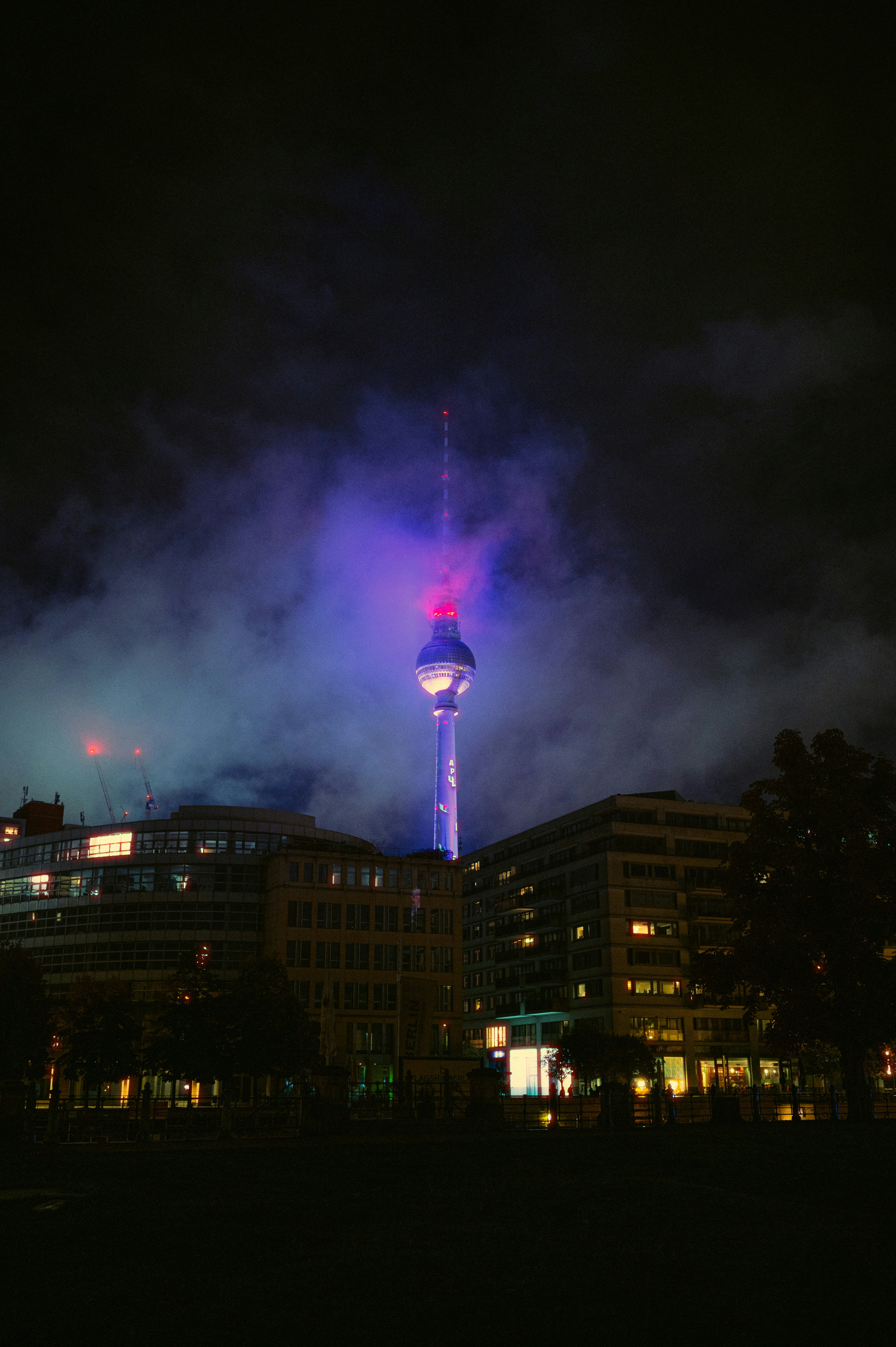 Tall tower illuminated at night with surrounding buildings