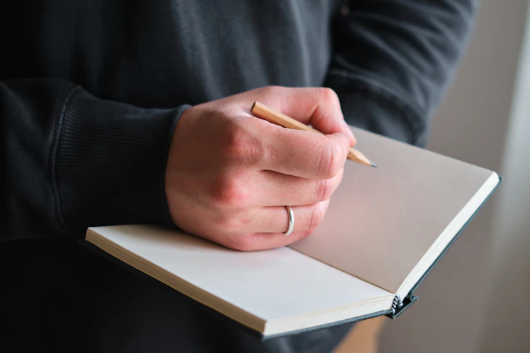 Persona escribiendo en un cuaderno como símbolo de la libertad y responsabilidad del autor