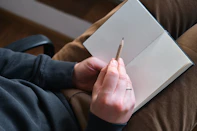 Person holding pencil over open notebook
