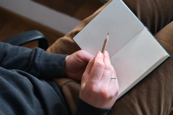 Person holding pencil over open notebook