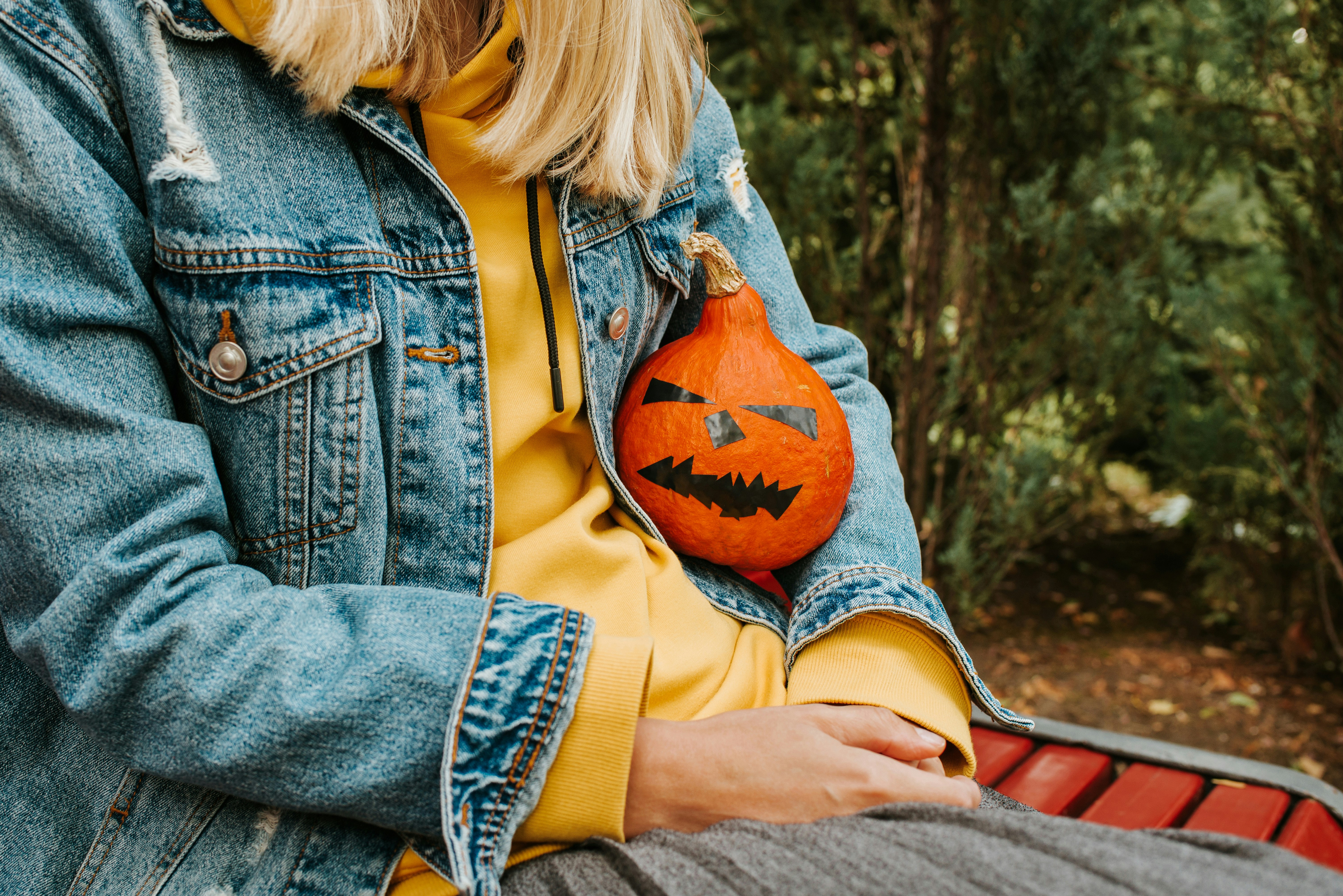 Person holding a small carved pumpkin with a face